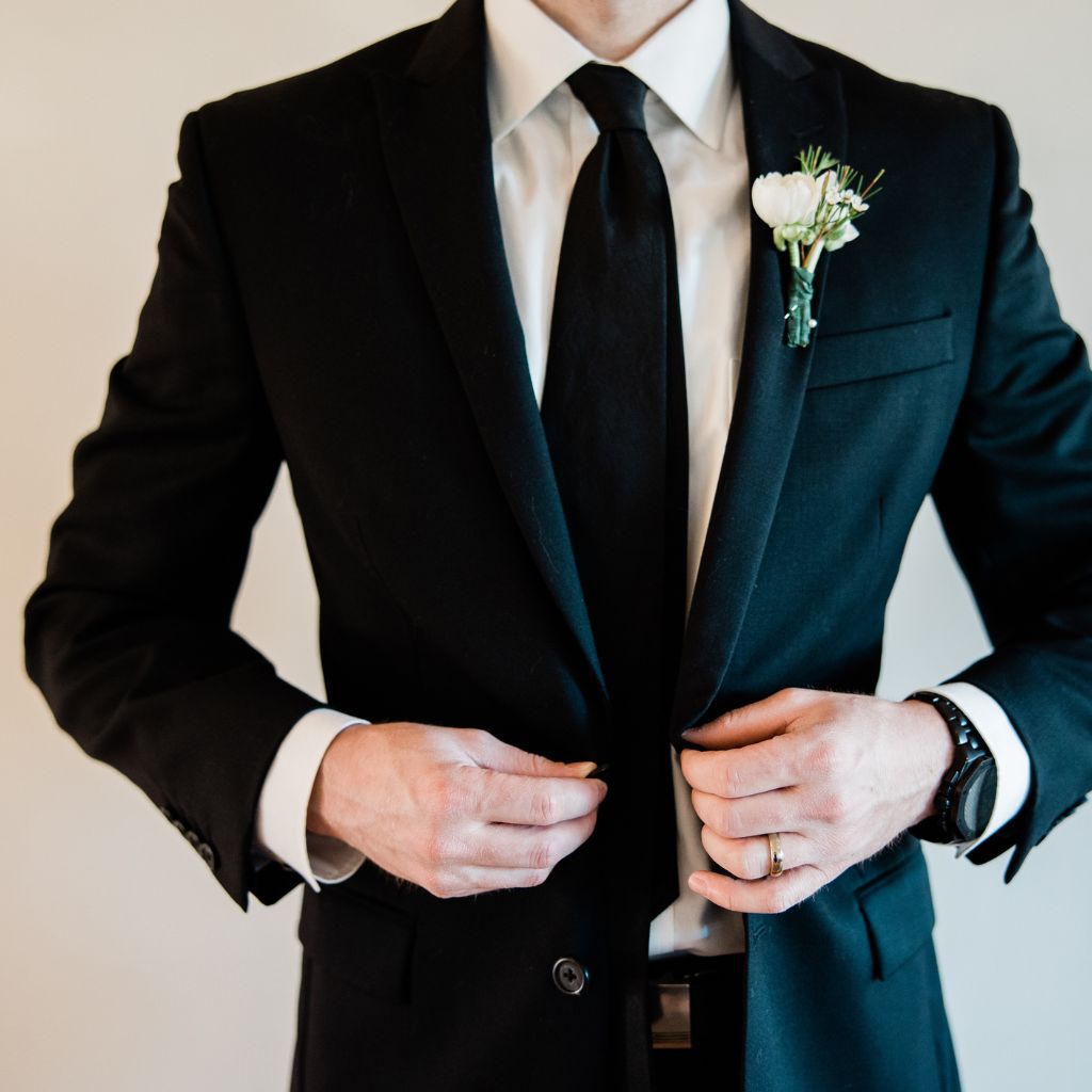 hombre con traje negro preparándose para su boda