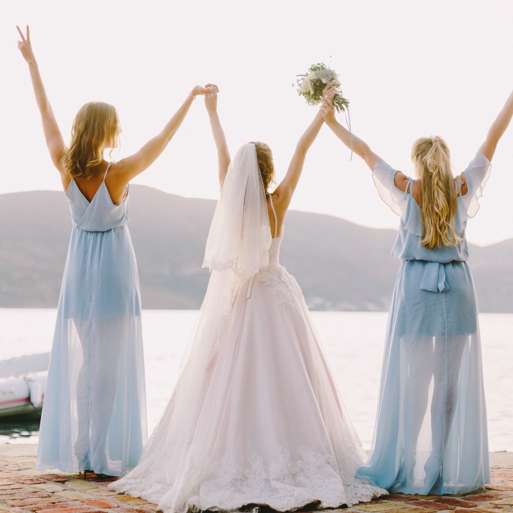 damas de honor con vestidos celeste junto a la novia vestida de blanco mirando el mar