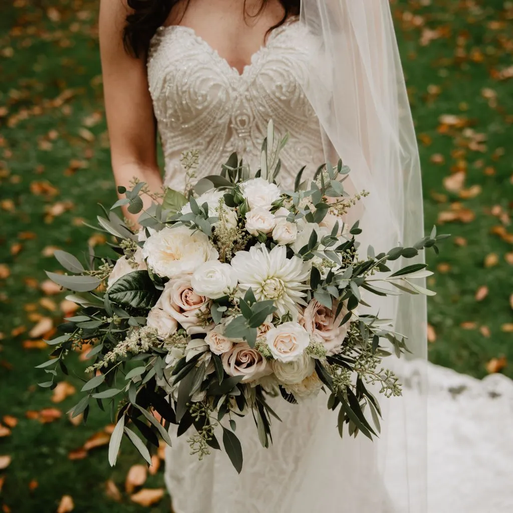 novia vestida de blanco con ramo de flores blanco