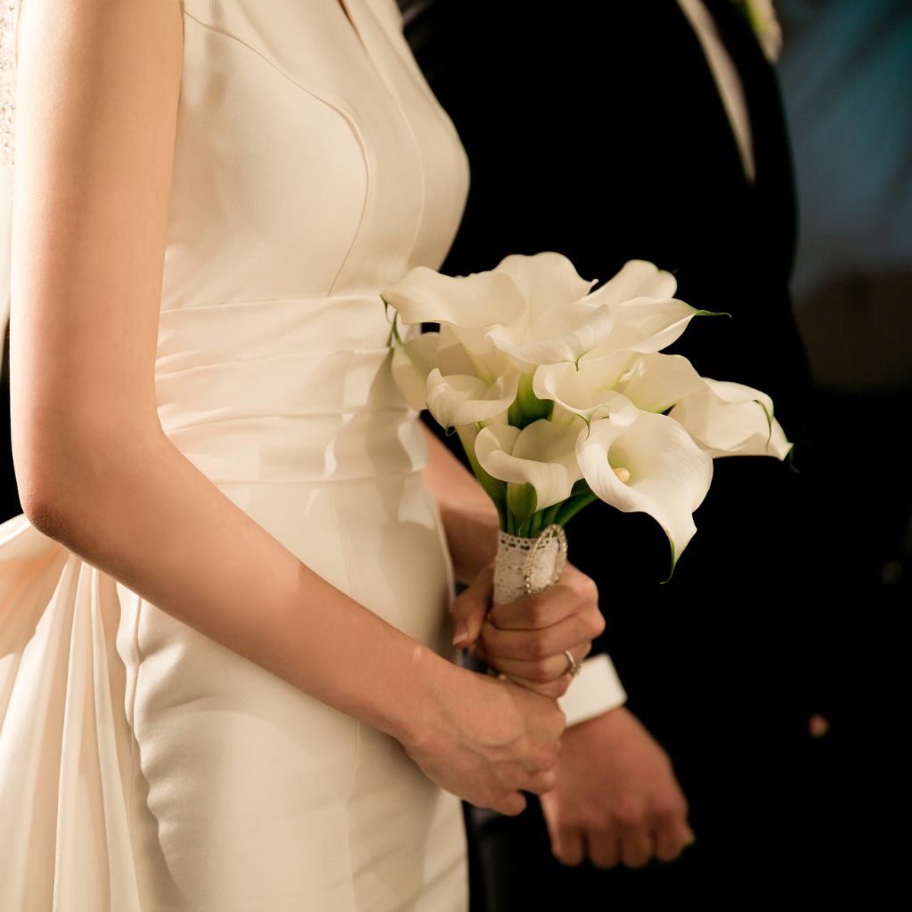 Novios y novia ingresando a una boda con un ramo blanco en la mano