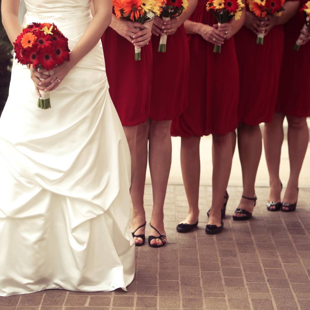 novia vestida de blanco con damas de honor vestidas de rojo