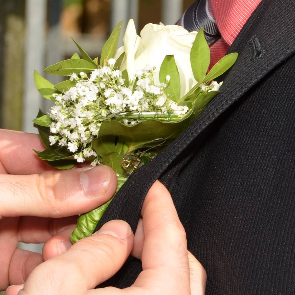 hombre colocando un ramillete a novio que se va a casar
